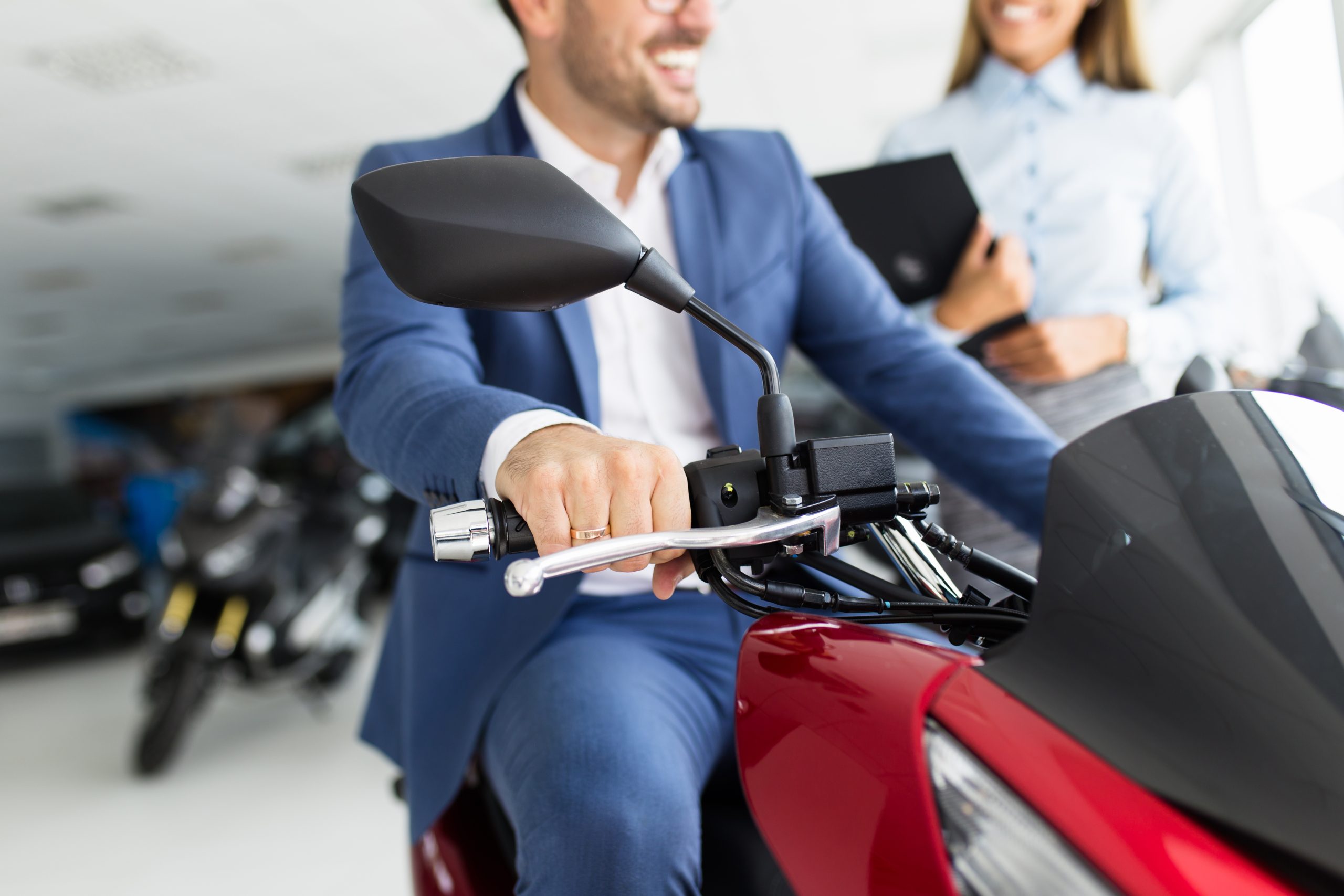 Young happy handsome man choosing a new motorcycle at motorcycle showroom.